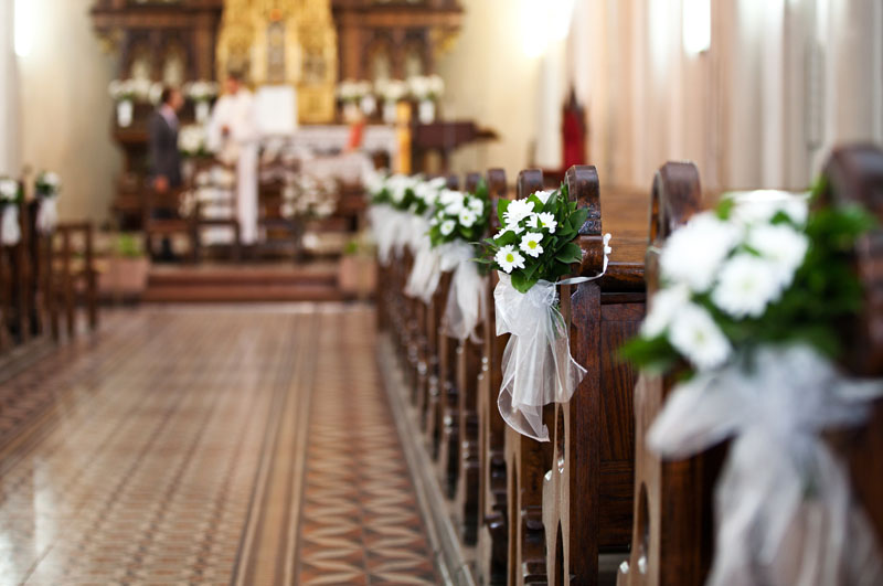 Kirchenbänke mit Blumensträußen und Tüll in Weiß geschmückt