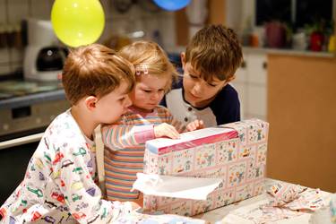 Geschwister packen zum 1. Geburtstag ein Geschenk aus