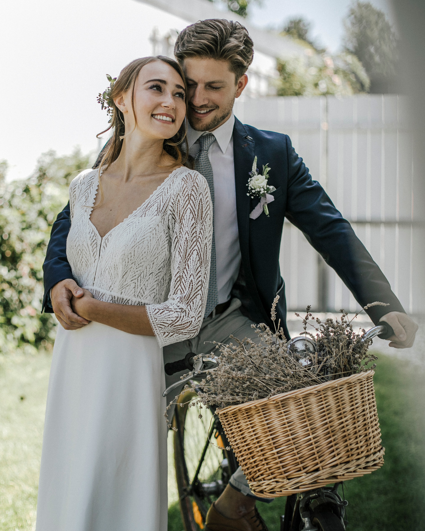 Glückliches Hochzeitspaar mit Fahrrad, dessen Korb mit Lavendel geschmückt ist