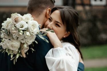 Hochzeitspaar umarmt sich mit Brautstrauß in der Hand