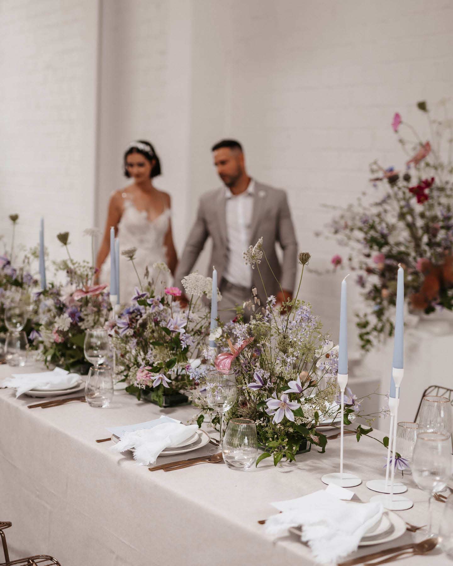 Hochzeitspaar läuft Hand in Hand zur Floral Chic Hochzeitstafel