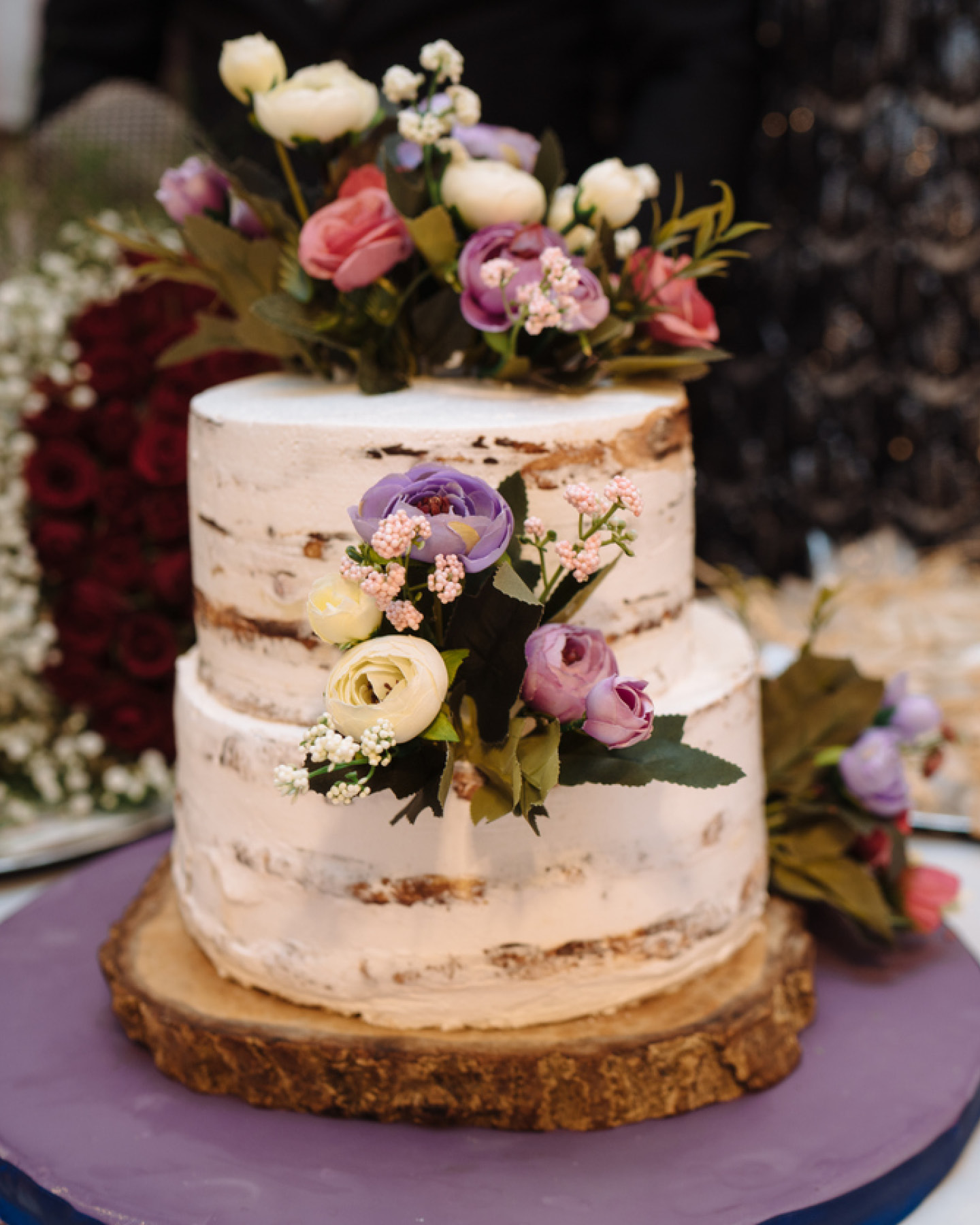 Zweistöckiger Naked Cake mit weißem Frosting und Blüten in weiß, Rosé und Lila