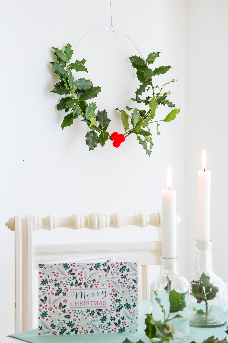 Kleine Glasflaschen mit Zweigen befüllt werden zur Weihnachtstischdeko.