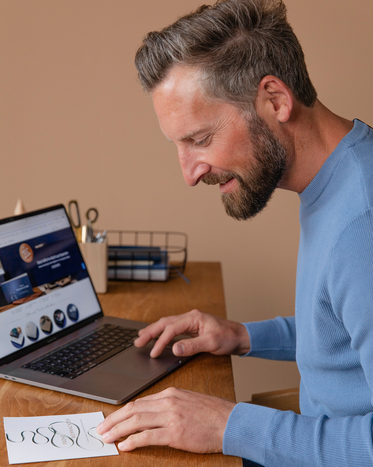 Mann sitzt am Laptop und gestaltet Einladung zur Weihnachtsfeier