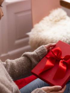 Oma sitzt mit zwei Kindern vor dem Weihnachtsbaum und schaut ein Bild an.