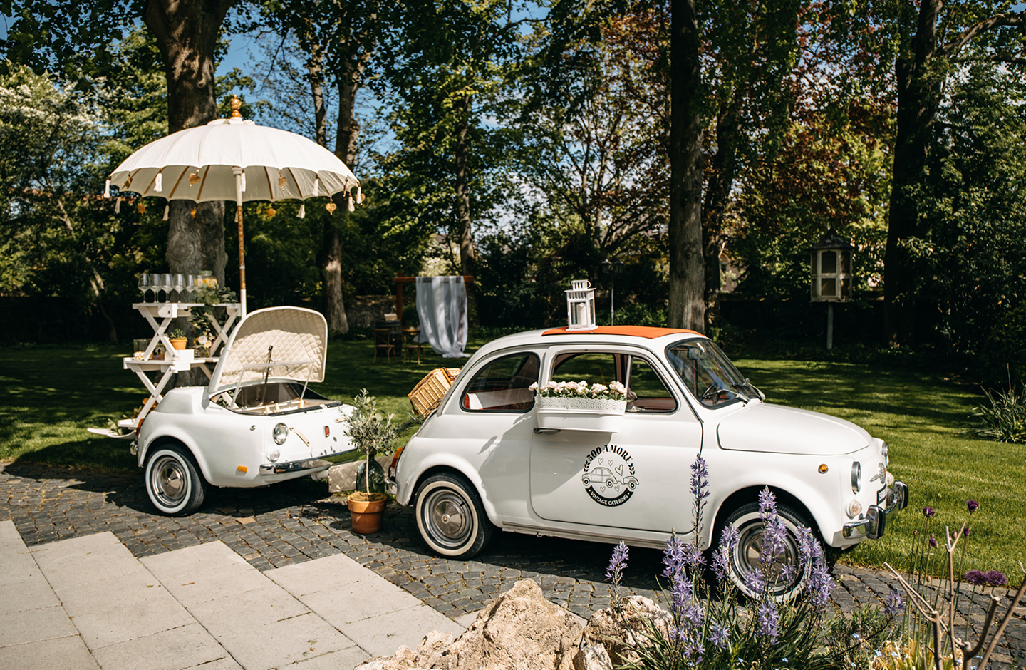 Oldtimer mit Anhänger steht auf der Terrasse am Weingut. Der umgebaute Anhänger wird als Sektkühlung genutzt.