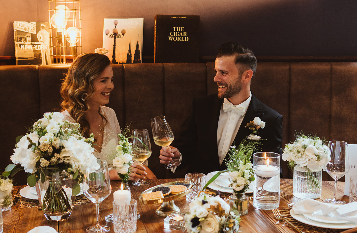 Das Hochzeitspaar stößt gemeinsam am Hochzeitstisch mit Getränken an