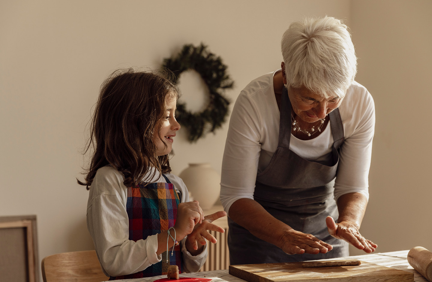 Oma und ihre Enkelin beim Ausrollen eines Teigstücksfür Weihnachtsplätzchen