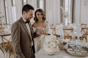 Glückliches Brautpaar schneidet nach der Trauung auf dem Standesamt die Hochzeitstorte an