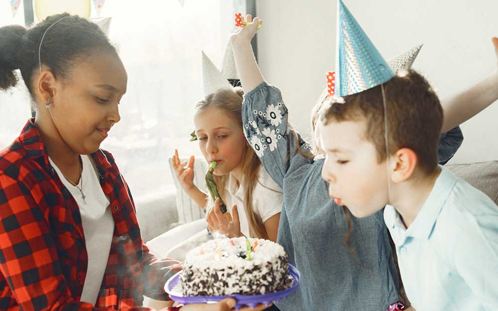 Kind bläst Kerze auf Kuchen aus