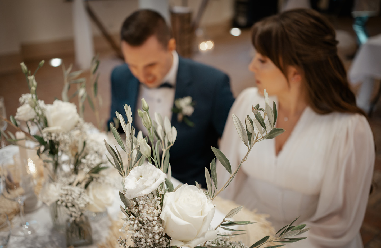 Braut und Bräutigam sitzen am geschmückten Hochzeitstisch.