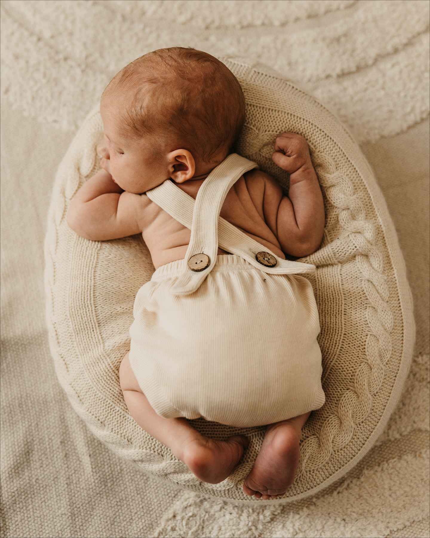 Baby in Latzshorts auf dem Bauch liegend